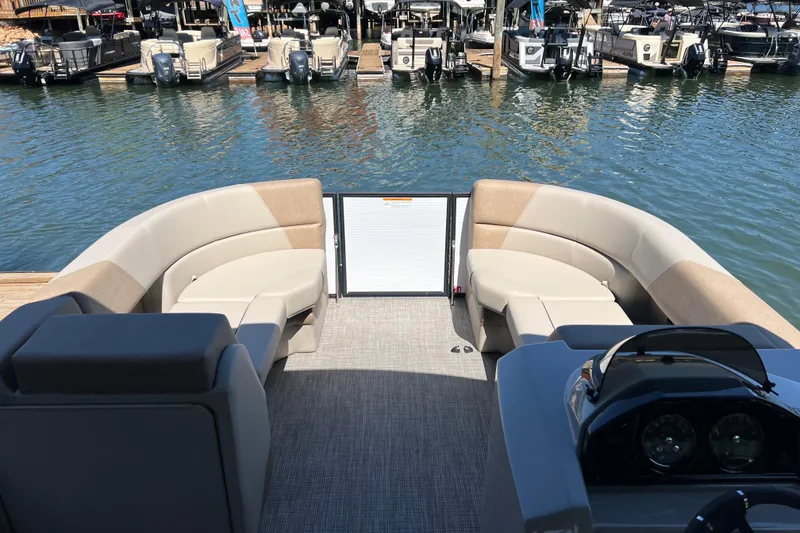 Slide: The Image of 2026 Manitou 23 Aurora LE RF pontoon boat interior with plush seating, docked at marina. - 7
