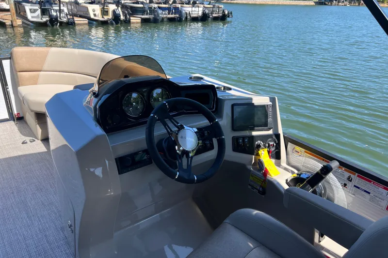 Slide: The Image of 2026 Manitou 23 Aurora LE RF boat interior with steering console and lake view. - 8