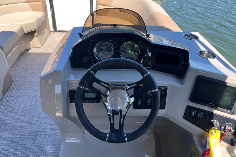 Slide: The Image of 2026 Manitou 23 Aurora LE RF boat dashboard with steering wheel and controls. - 9