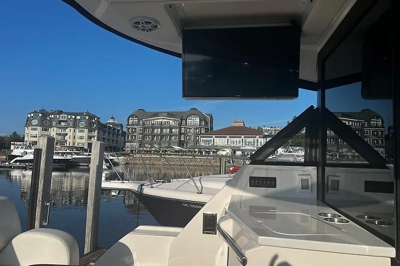 Slide: The Image of 2024 Regal 38 Grande Coupe yacht docked at marina with waterfront buildings in background. - 10