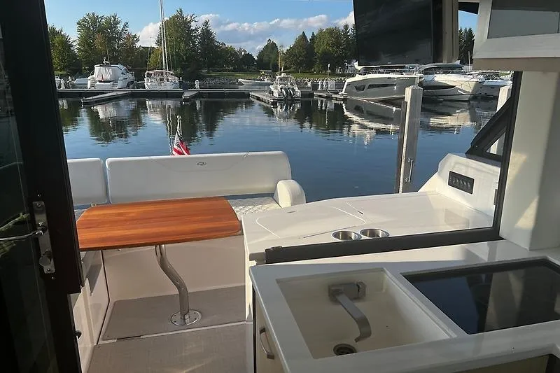Slide: The Image of 2024 Regal 38 Grande Coupe yacht interior with kitchenette and marina view. - 11