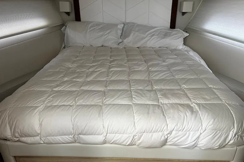 Slide: The Image of Luxurious bed inside 2024 Regal 38 Grande Coupe yacht cabin, featuring plush white bedding. - 24