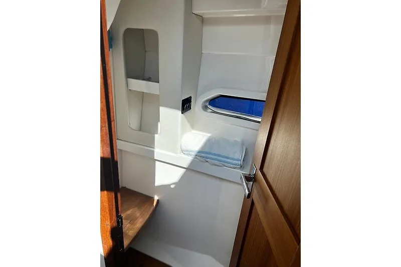 Slide: The Image of 2024 Regal 38 Grande Coupe interior cabin with window, shelf, and wooden door. - 25