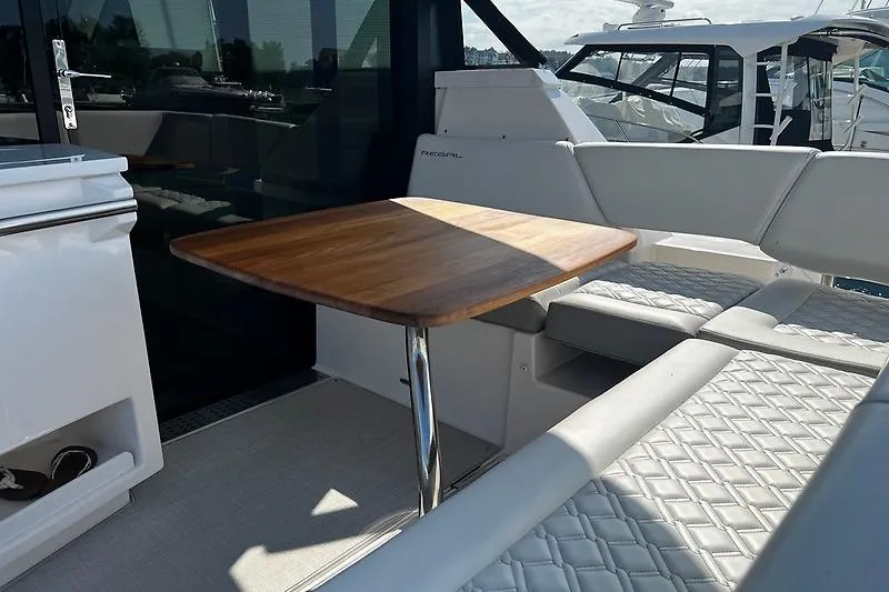 Slide: The Image of 2024 Regal 38 Grande Coupe yacht interior with elegant seating and wooden table. - 8