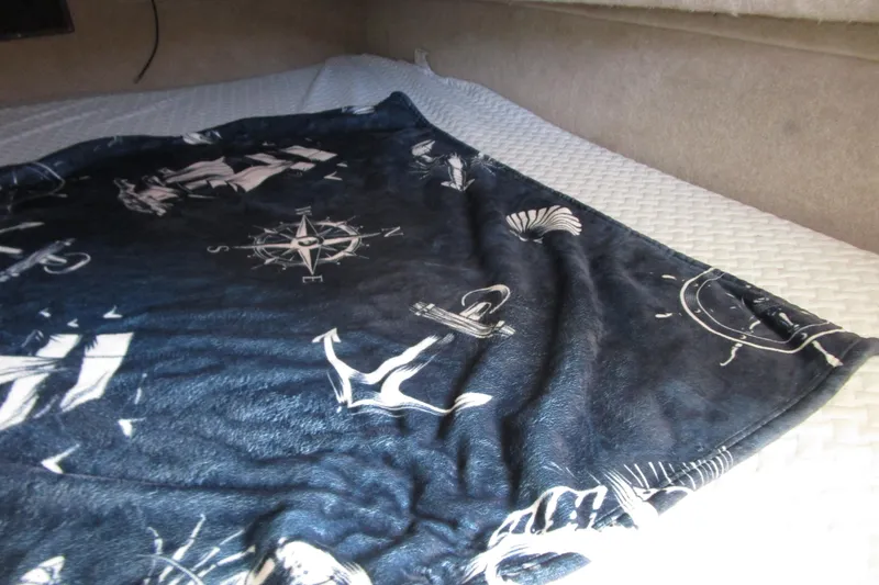 Slide: The Image of Nautical-themed blanket on a bed inside a 1989 Bayliner 3288 Motoryacht cabin. - 18