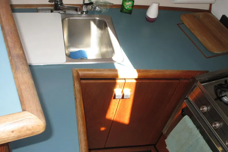 Slide: The Image of 1989 Bayliner 3288 Motoryacht kitchen with sink, stove, and wooden cabinetry. - 7