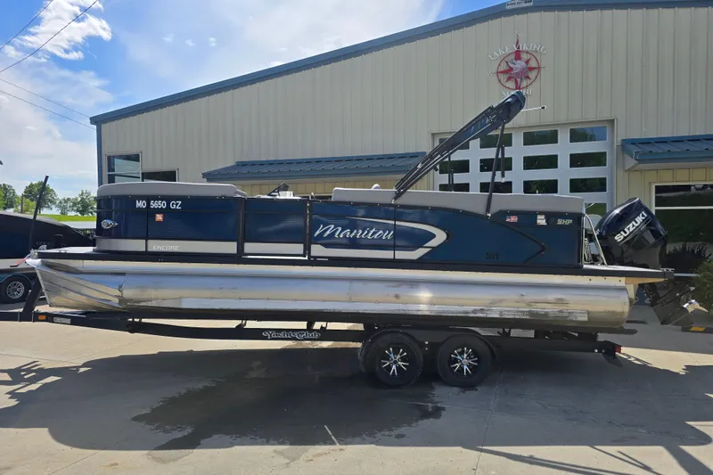Slide: The Image of 2022 Manitou 23 Encore RF pontoon boat on trailer outside a building. - 1