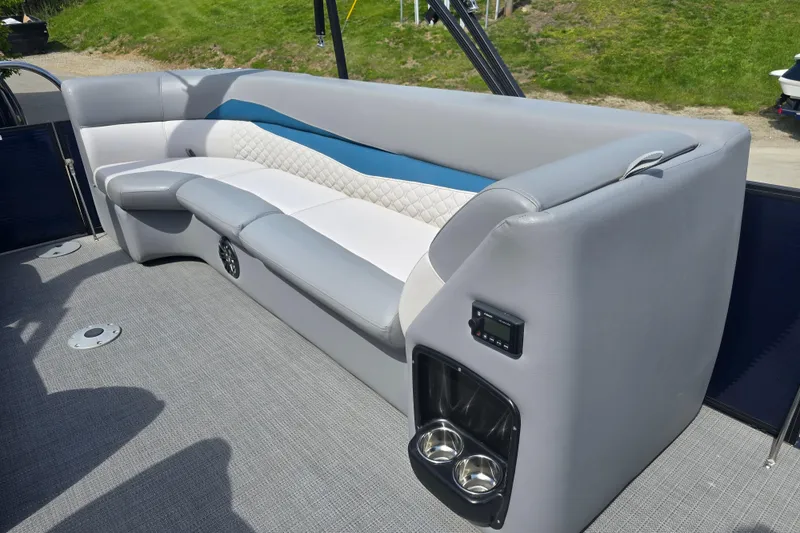 Slide: The Image of 2022 Manitou 23 Encore RF boat interior with gray and white seating, cup holders, and speaker. - 15