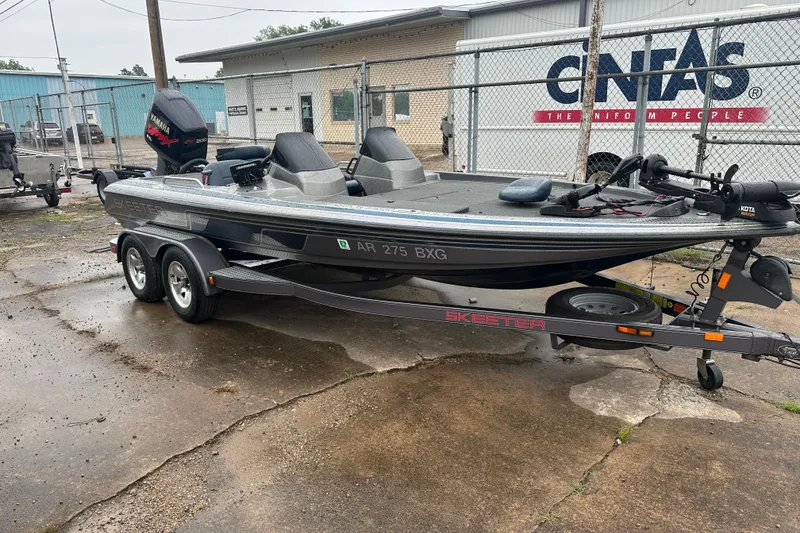 Slide: The Image of 1999 Skeeter ZX1950 boat on trailer, parked outdoors near industrial buildings. - 17