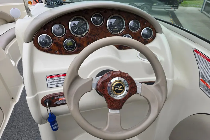 Slide: The Image of Steering wheel and dashboard of 2003 Sea Ray 220 Sundeck boat, featuring wood accents and gauges. - 12