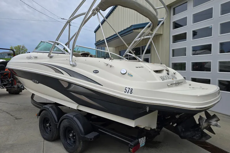 Slide: The Image of 2003 Sea Ray 220 Sundeck boat on trailer, parked near a garage. - 2