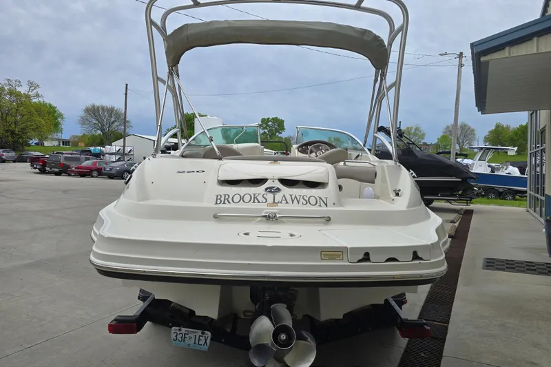 Slide: The Image of 2003 Sea Ray 220 Sundeck boat with canopy, parked outdoors on a concrete surface. - 3