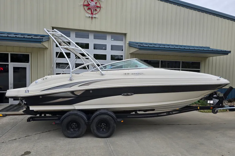 Slide: The Image of 2003 Sea Ray 220 Sundeck boat on trailer, parked outside a marine building. - 5