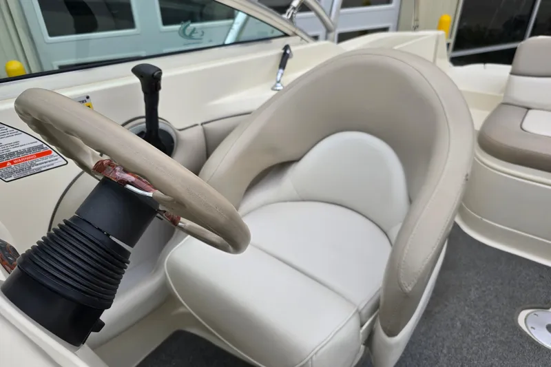 Slide: The Image of 2003 Sea Ray 220 Sundeck boat interior with steering wheel and cushioned seating. - 9