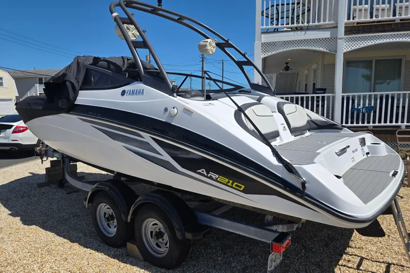 The Image of 2018 Yamaha AR210 boat on trailer, parked outdoors near a house. - 0