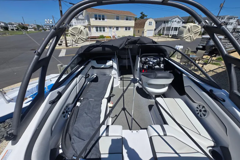 Slide: The Image of 2018 Yamaha Boats AR210 interior with seating and steering wheel, parked in a residential area. - 12