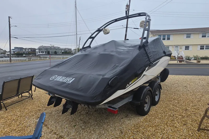 Slide: The Image of 2018 Yamaha AR210 boat covered on trailer, parked in residential area. - 14