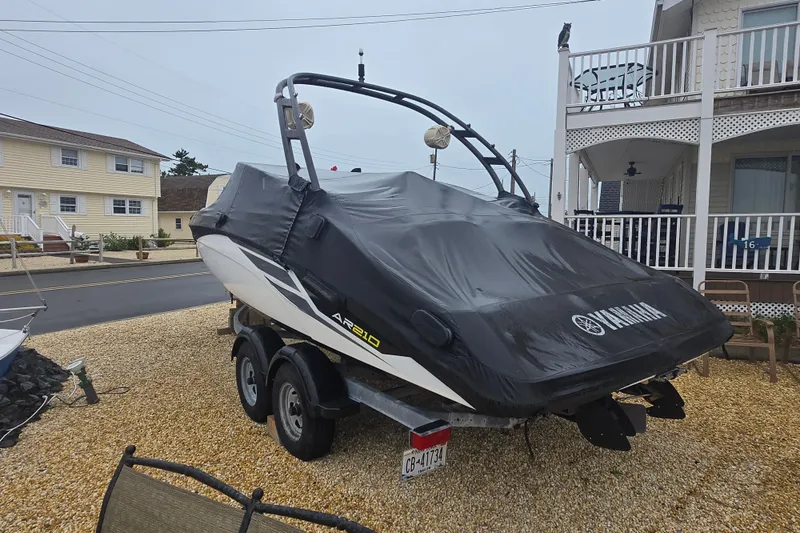Slide: The Image of 2018 Yamaha AR210 boat covered on a trailer in a residential area. - 16