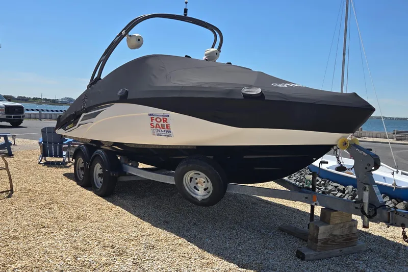 Slide: The Image of 2018 Yamaha AR210 boat for sale on trailer, covered and parked near waterfront. - 2