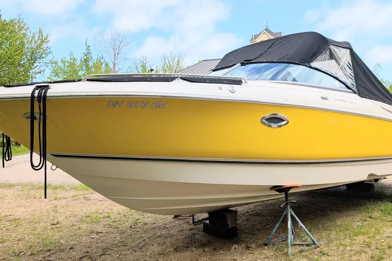 The Image of Yellow 2007 Monterey 248LS Montura Bowrider boat on land, with black canopy. - 0