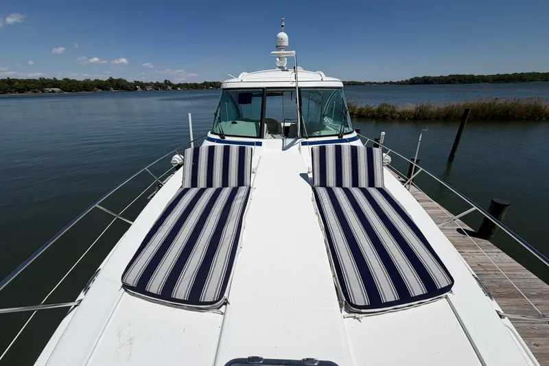 Slide: The Image of 2011 Formula 45 Yacht with striped sun loungers on deck, docked by serene waters. - 4