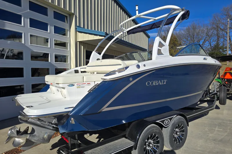 Slide: The Image of 2020 Cobalt R3 boat in blue, parked on a trailer outside a garage. - 6