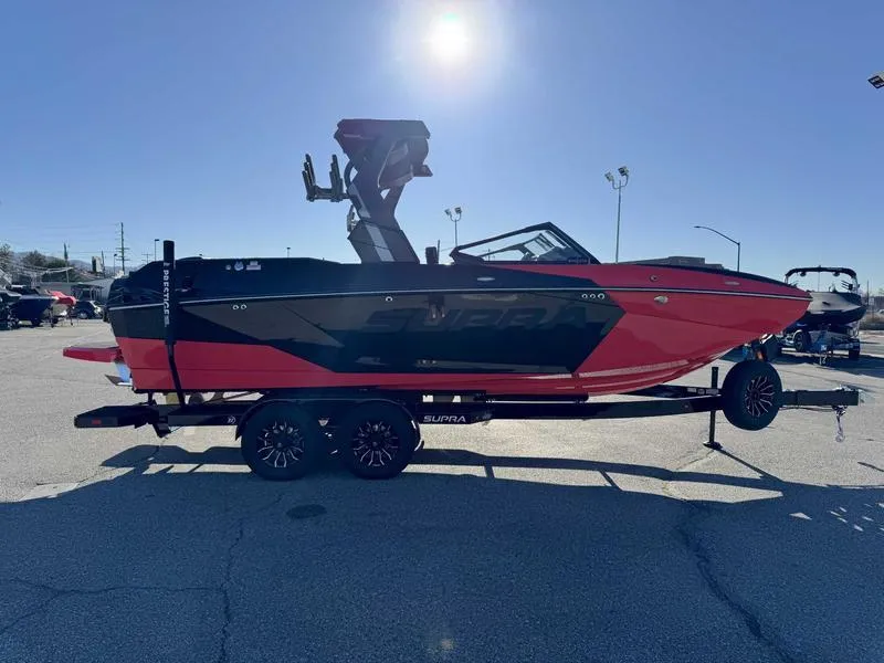 Slide: The Image of 2025 Supra SA boat in red and black on a trailer, parked outdoors. - 4