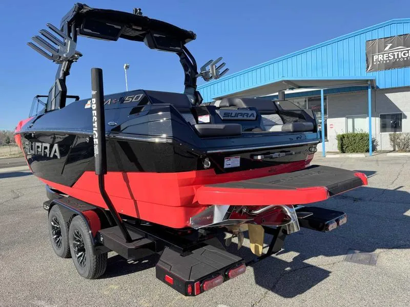 Slide: The Image of 2025 Supra SA boat on trailer, red and black design, parked outside a blue building. - 5