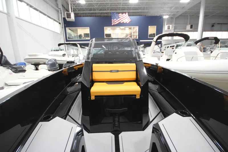 Slide: The Image of 2026 Iron 767 boat with yellow seating, displayed indoors under American flag. - 24