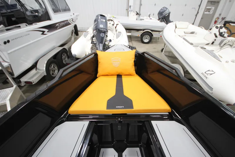 Slide: The Image of Modern Iron 767 boat interior with orange cushion, sleek design, and adjacent boats in showroom. - 28