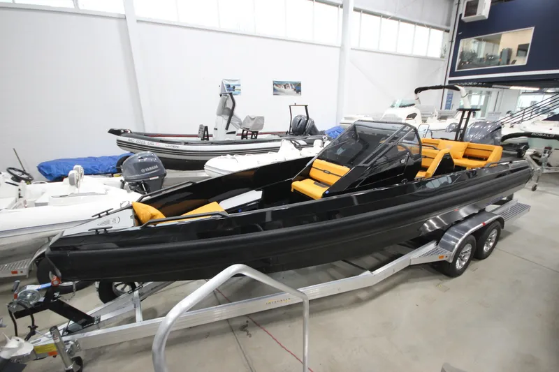 Slide: The Image of 2026 Iron 767 boat with sleek black design and orange seating on a trailer in showroom. - 3
