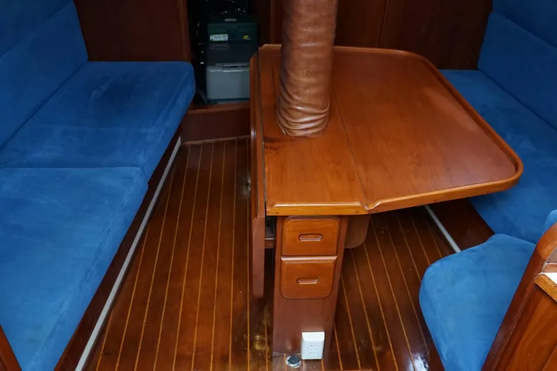 Slide: The Image of Interior of a 1987 Morgan 43 yacht with wooden table and blue seating. - 11