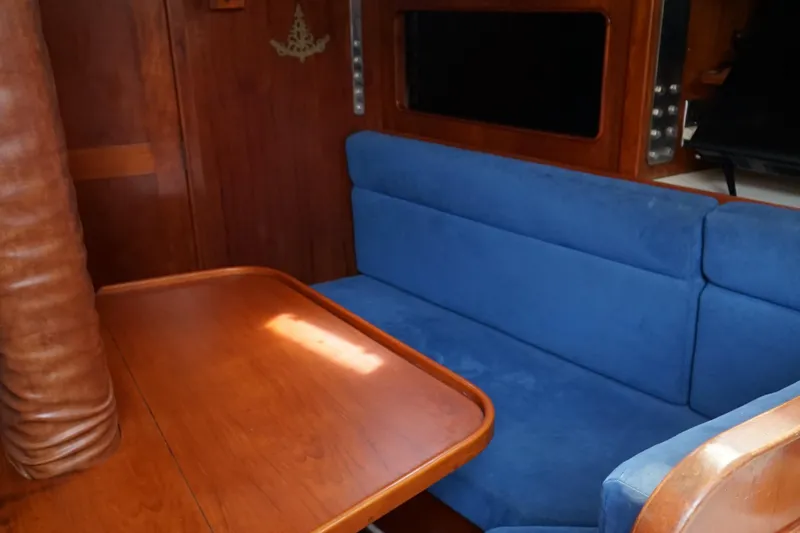 Slide: The Image of Interior of a 1987 Morgan 43 yacht with blue seating and wooden table. - 12