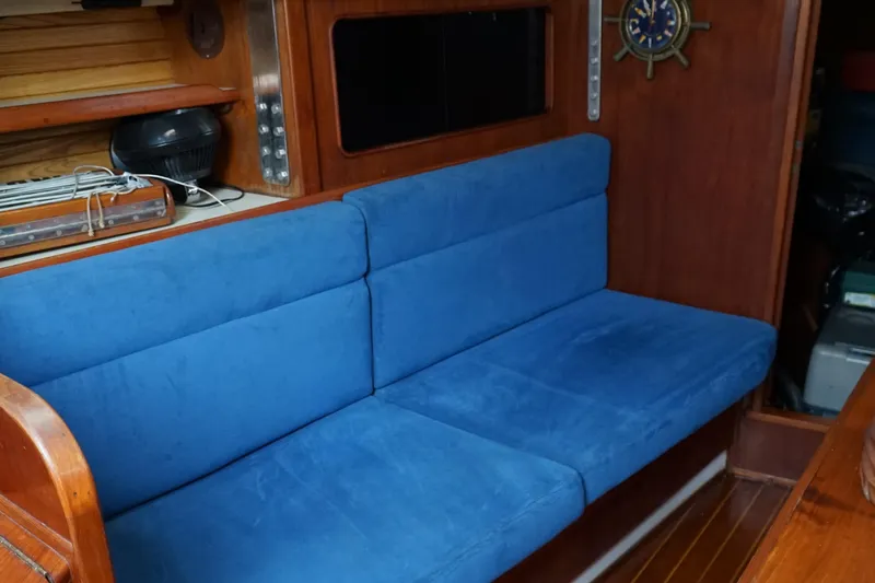 Slide: The Image of Interior of 1987 Morgan 43 yacht with blue cushioned seating and wooden paneling. - 13