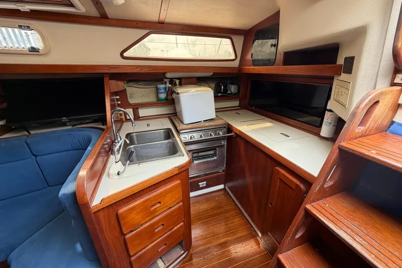 Slide: The Image of 1987 Morgan 43 yacht interior kitchen with wooden cabinetry and blue seating. - 16