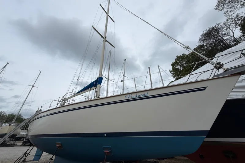 Slide: The Image of 1987 Morgan 43 sailboat named Windswept, docked under cloudy skies. - 3