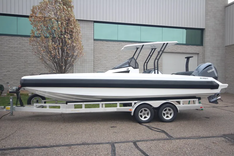 Slide: The Image of 2026 Iron 767 boat on trailer, parked outdoors near industrial building. - 2