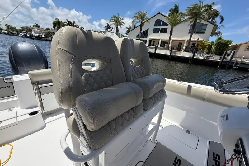 Slide: The Image of 2021 Sportsman Open 252 Center Console boat with plush seating, docked by waterfront homes. - 10