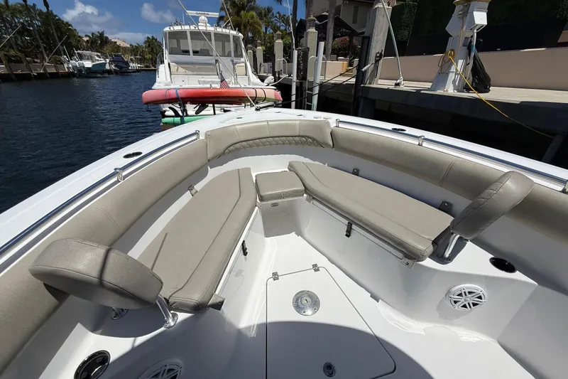 Slide: The Image of 2021 Sportsman Open 252 Center Console boat interior with cushioned seating and docked view. - 14
