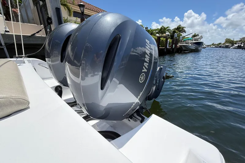Slide: The Image of Twin Yamaha outboard engines on a 2021 Sportsman Open 252 Center Console boat by the water. - 2