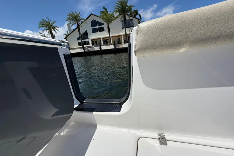 Slide: The Image of 2021 Sportsman Open 252 Center Console boat near waterfront house and palm trees. - 8