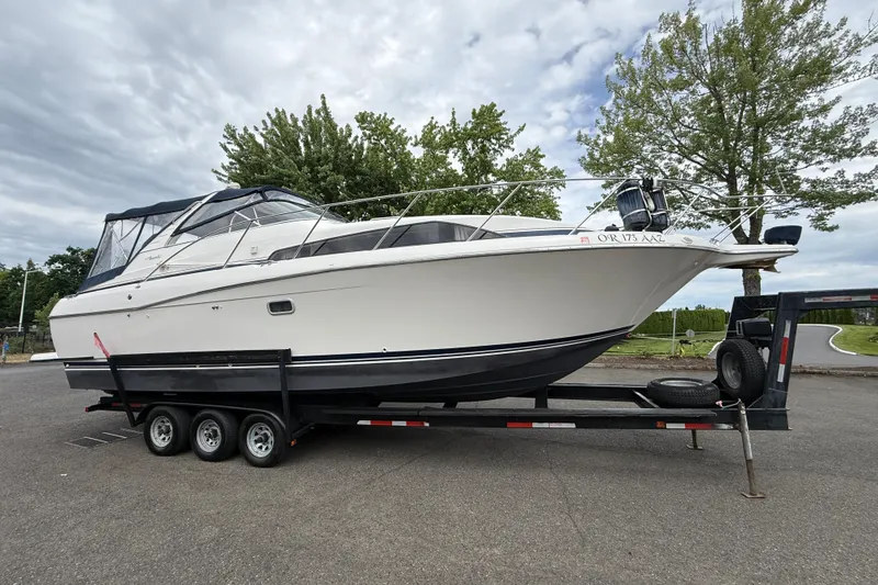 The Image of 1997 Bayliner 3255 Avanti boat on trailer, parked outdoors under cloudy sky. - 0