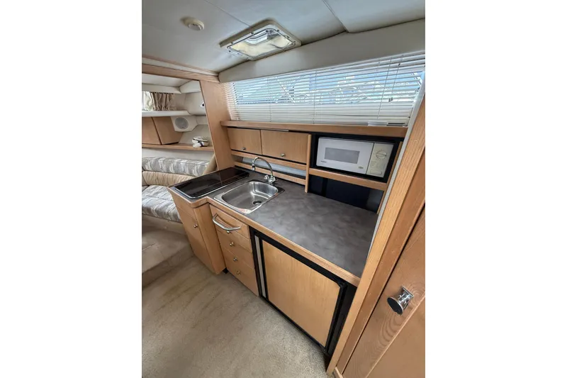 Slide: The Image of Interior of 1997 Bayliner 3255 Avanti boat featuring kitchenette with sink and microwave. - 14