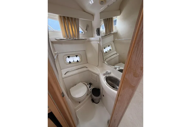 Slide: The Image of 1997 Bayliner 3255 Avanti boat bathroom with toilet, sink, and porthole window. - 15