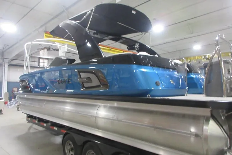 Slide: The Image of 2026 Tahoe pontoon boat in a showroom, featuring a sleek blue design and modern amenities. - 2