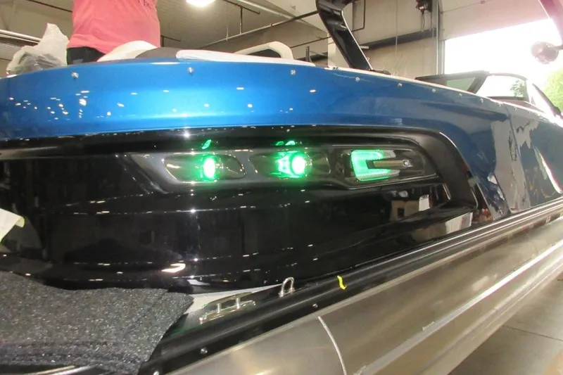 Slide: The Image of 2026 Tahoe boat with sleek blue design and illuminated green lights in a showroom. - 6