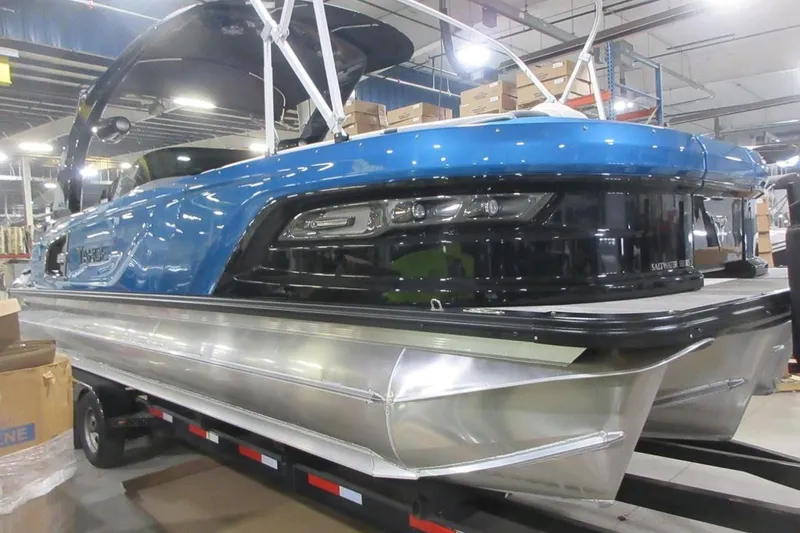Slide: The Image of 2026 Tahoe pontoon boat with sleek blue design in a warehouse setting. - 9