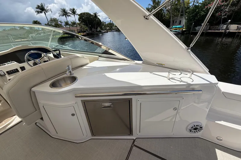 Slide: The Image of 2022 Regal 33 XO yacht interior with sink and storage, docked by a scenic canal. - 12