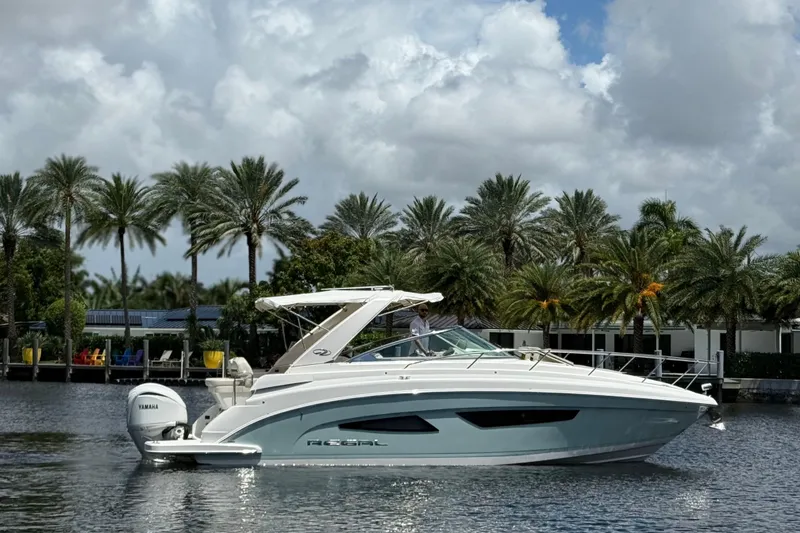 Slide: The Image of 2022 Regal 33 XO boat cruising on a scenic waterway with palm trees in the background. - 2