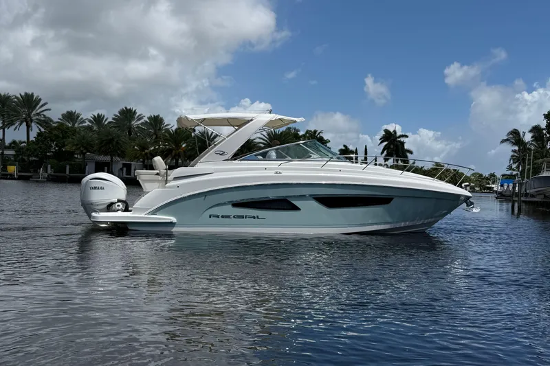 Slide: The Image of 2022 Regal 33 XO boat on calm water with palm trees in the background. - 3